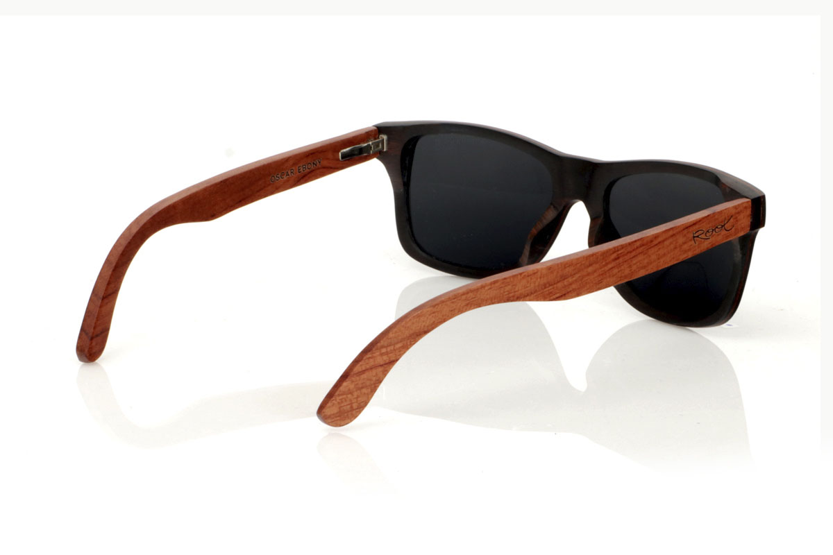 Wood eyewear of Ebony OSCAR. Gafas de sol de madera OSCAR, destaca su estilo inspirado en los clásicos, ofreciendo una silueta ancha que capta la atención. Estas gafas están meticulosamente fabricadas en capas de madera laminada, combinando ébano en el exterior y caoba en el centro, creando un efecto visual único y elegante, realzado por remaches plateados en el frontal. Las varillas de caoba prometen no solo estilo, sino también una durabilidad excepcional. Además de su diseño impecable, las OSCAR garantizan una visión clara y una protección total, asegurando que tus ojos estén protegidos con el máximo confort. Medidas: 149x45 mm. Calibre: 54. Con las OSCAR, experimentarás la perfecta unión entre moda y funcionalidad. for Wholesale & Retail | Root Sunglasses® 